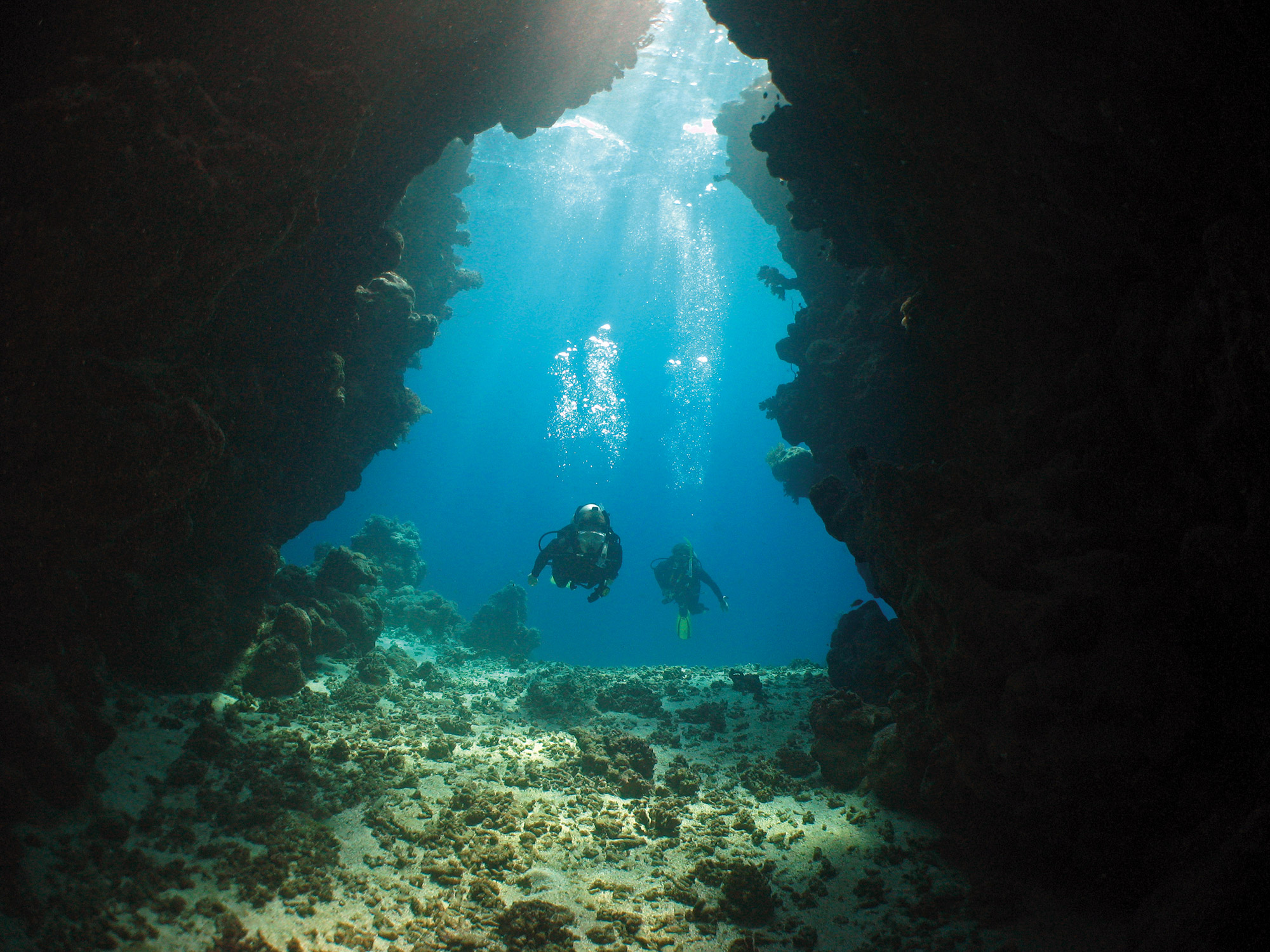Divers enter a large underwater cavern on a Red Sea coral reef